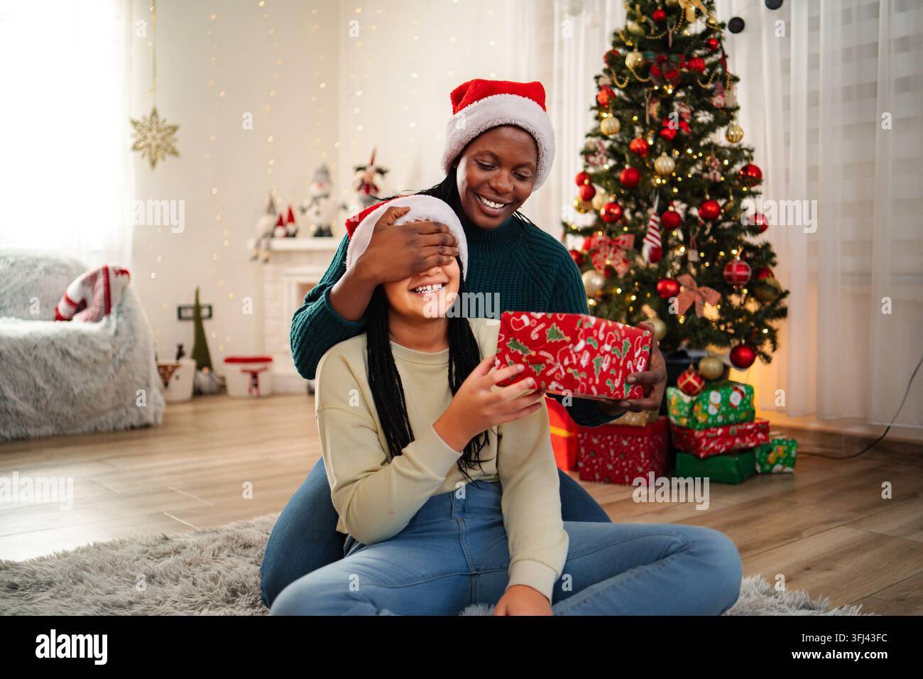 Madre che regala alla figlia un regalo a sorpresa di Natale a casa Foto Stock