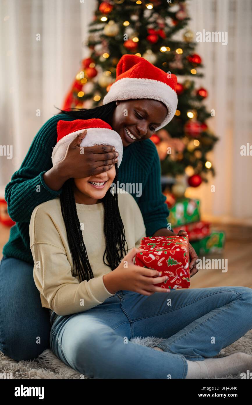 Madre che regala un regalo di Natale alla figlia come sorpresa Foto Stock