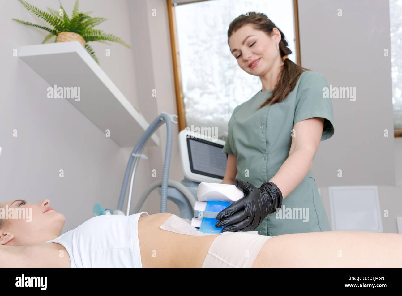Trattamento di contorno del corpo con criolipolisi sull'addome di una donna Foto Stock