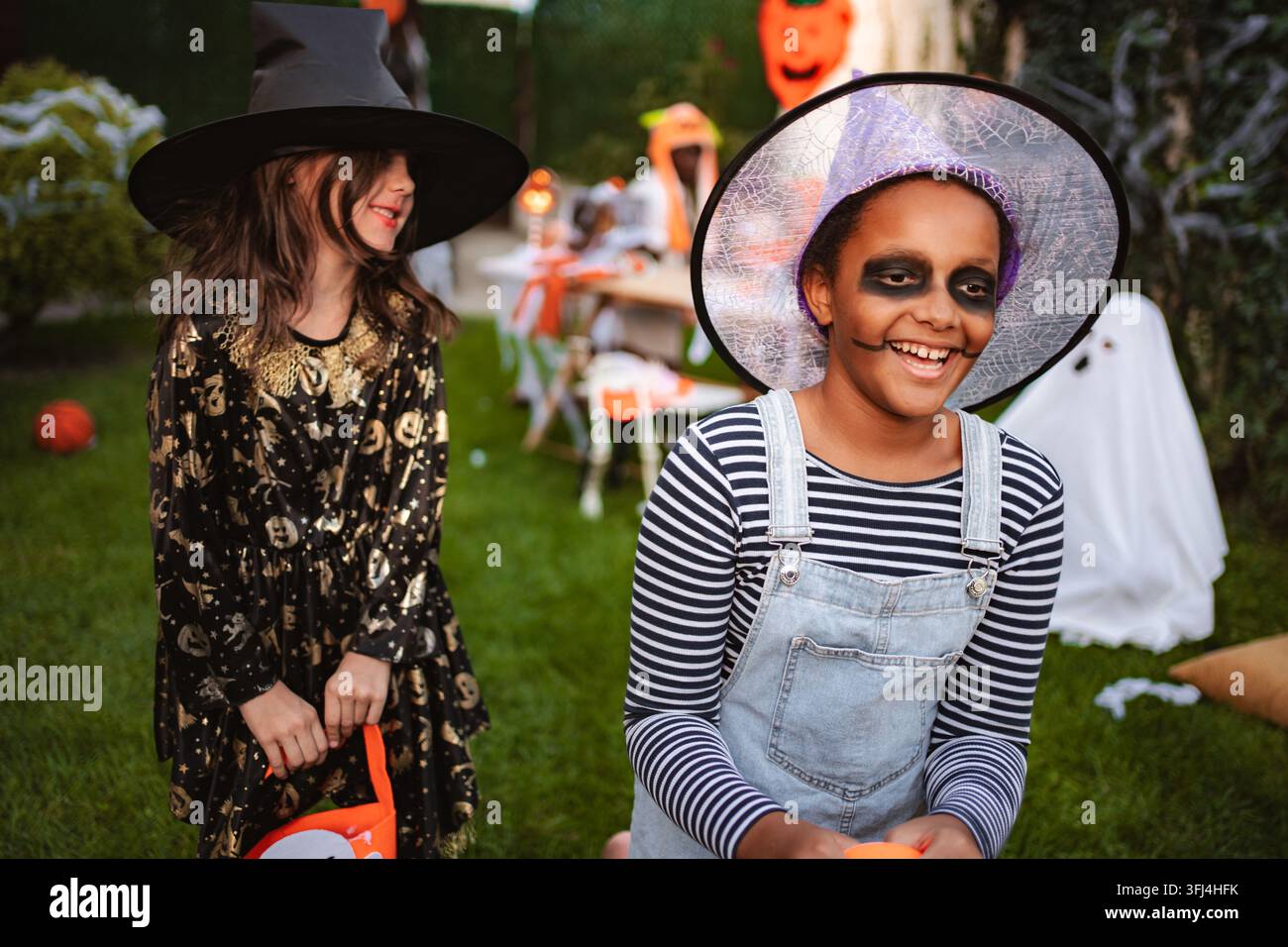 Ragazze diverse che celebrano una festa di Halloween all'aperto indossando costumi da strega Foto Stock