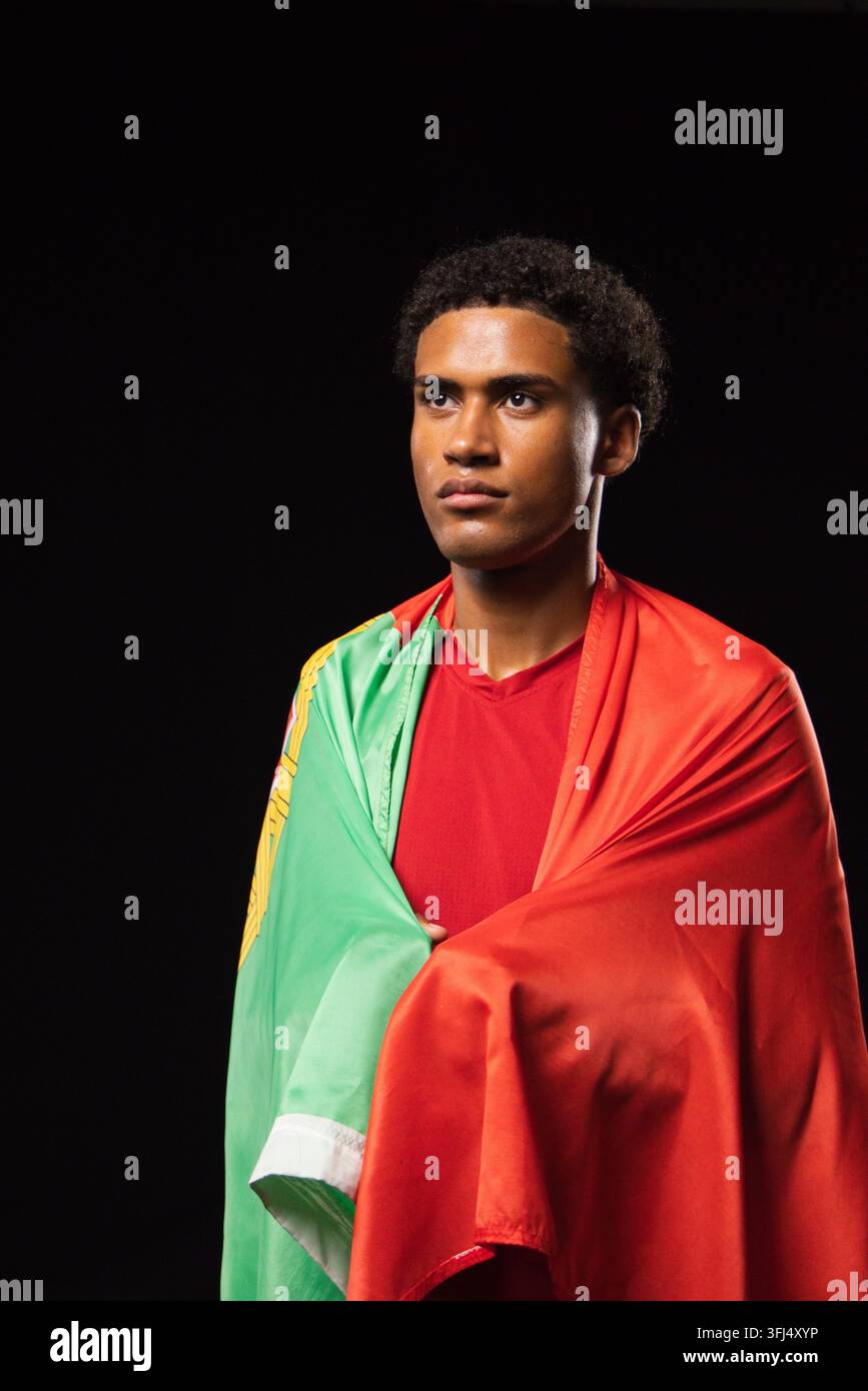 Uomo afroamericano in piedi in studio con una bandiera rossa verde con emblema giallo, maglia a collo rotondo. Ritratto, drappeggiato, capo di abbigliamento, u Foto Stock