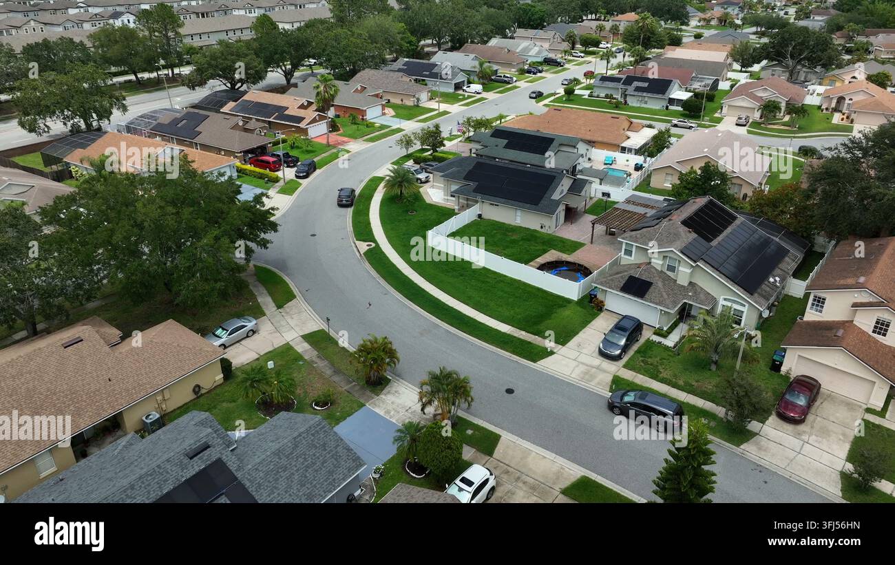 Vista aerea di un quartiere americano esclusivo a Orlando con case di lusso, prati curati, strade curve e traffico sulla strada. Zona residenziale elegante Foto Stock