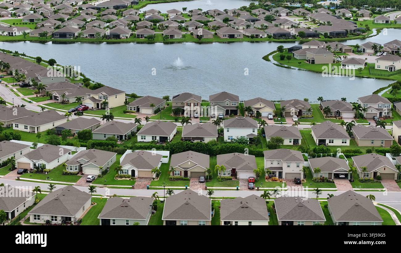 Un quartiere suburbano circonda un lago scenografico con una fontana nella Florida centrale. File di case con prati e vialetti curati si estendono al Foto Stock