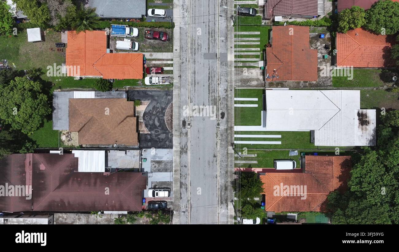 Via residenziale nella periferia della Florida, fiancheggiata da case monofamiliari e auto parcheggiate. I vialetti portano direttamente alla strada principale, creando una griglia simile a una rete Foto Stock