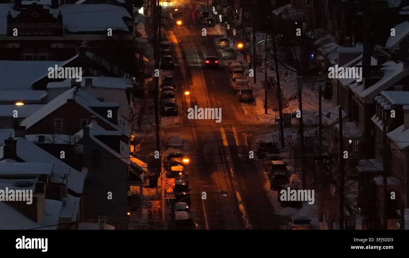 Auto su strada ghiacciata di un quartiere americano in una fredda notte d'inverno. Punto di lanterna arancione luminoso. Strada in un quartiere di periferia. Scena invernale tranquilla e pacifica Foto Stock