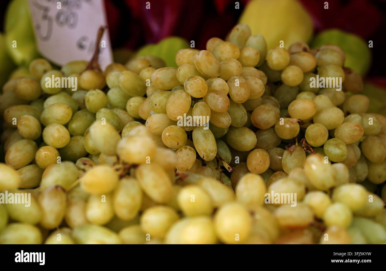Uva verde ammucchiata su un banco di mercato, matura, succosa e fresca alla luce naturale del giorno, evidenziando prodotti abbondanti e sani pronti per l'acquisto e sn Foto Stock