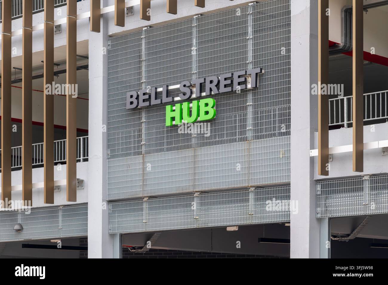 Facciata moderna di un parcheggio a più piani con rivestimento in rete metallica, alette verticali effetto legno e grandi lettere verde illuminate del marchio Hub Foto Stock
