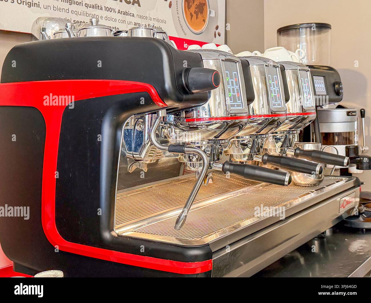 Milazzo - ME - IT - Set 09, 2026: Macchina da caffè commerciale con corpo rosso e nero, gruppi di erogazione cromati, portafiltri e tubo del vapore in un bar Foto Stock