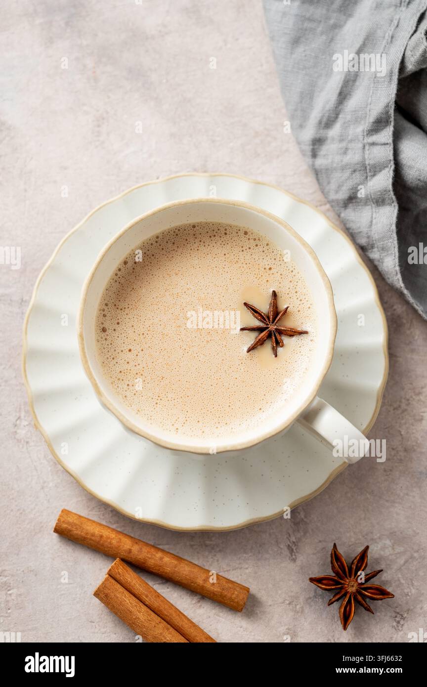 Tè masala chai indiano tradizionale con latte e spezie in una tazza bianca su uno sfondo chiaro con tovagliolo. Un concetto di bevanda calda etnica e accogliente per l'autunno o Foto Stock