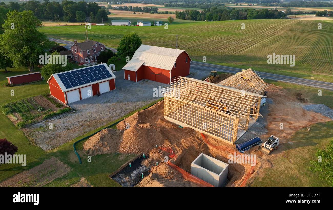 Vista aerea della costruzione di una nuova casa. Stalla con pannelli solari sullo sfondo. Rural USA, Contea di Rapho, Pennsylvania. Foto Stock