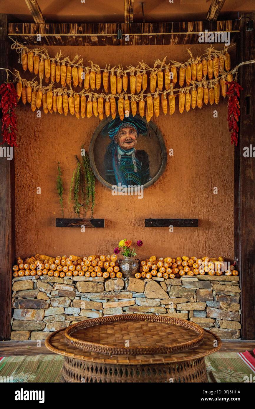 Decorazione d'interni rustica con mais essiccato e ritratto dipinto di un anziano Hmong, Y Ty, Lao Cai, Vietnam Foto Stock