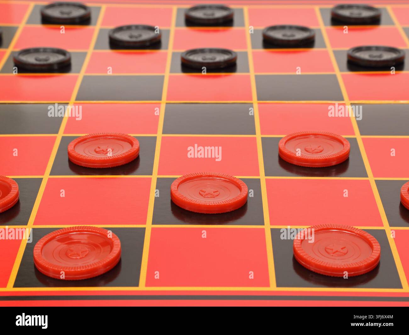Una partita a scacchi è mostrata su una scacchiera standard rossa e nera, pronta per il gioco. Foto Stock