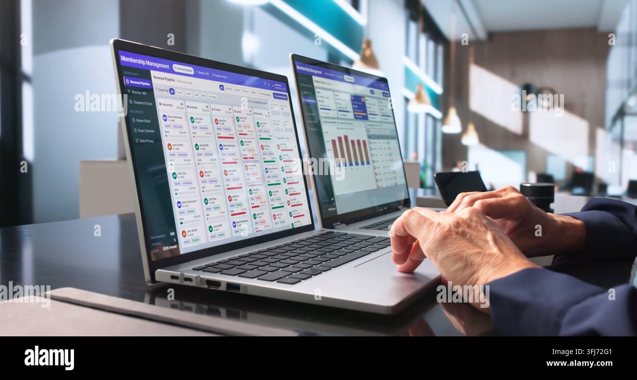 Il responsabile associativo aggiorna con attenzione il database dei membri utilizzando il software del laptop. Foto Stock