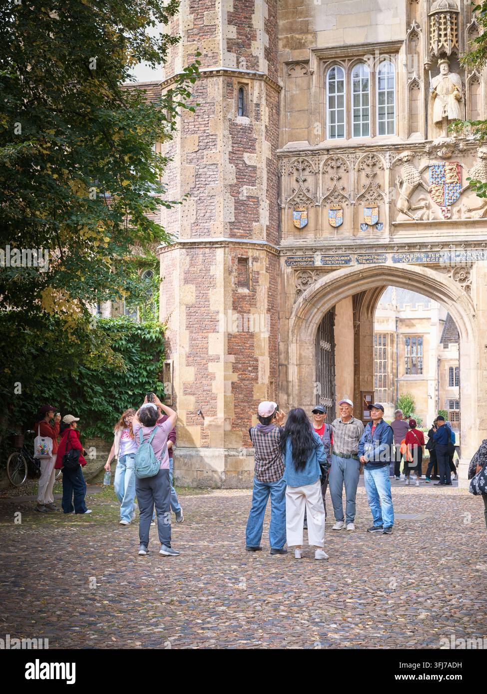Turisti cinesi posano per una foto all'ingresso del Trinity College, Università di Cambridge, Inghilterra. Foto Stock