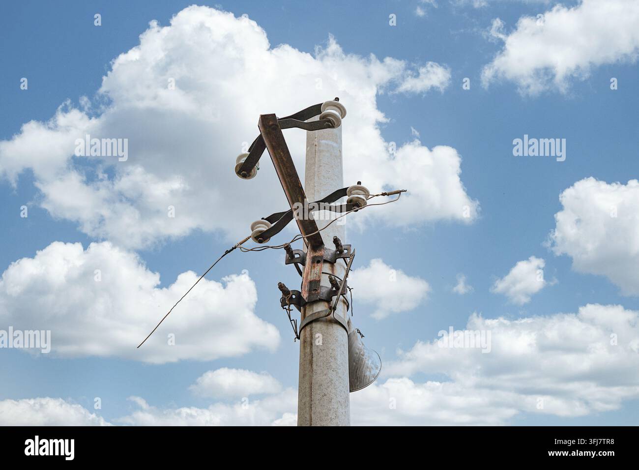 Vista ad angolo basso delle staffe metalliche in cima a un vecchio palo di servizio in cemento Foto Stock