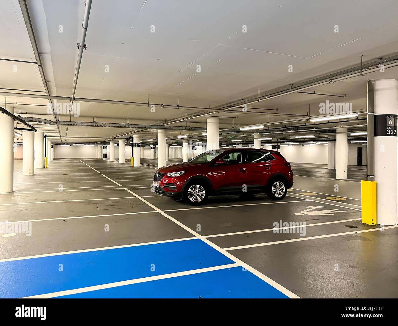 Un'auto solitaria parcheggiata su un piano in un parcheggio a più piani - Immagine stock catturata con smartphone