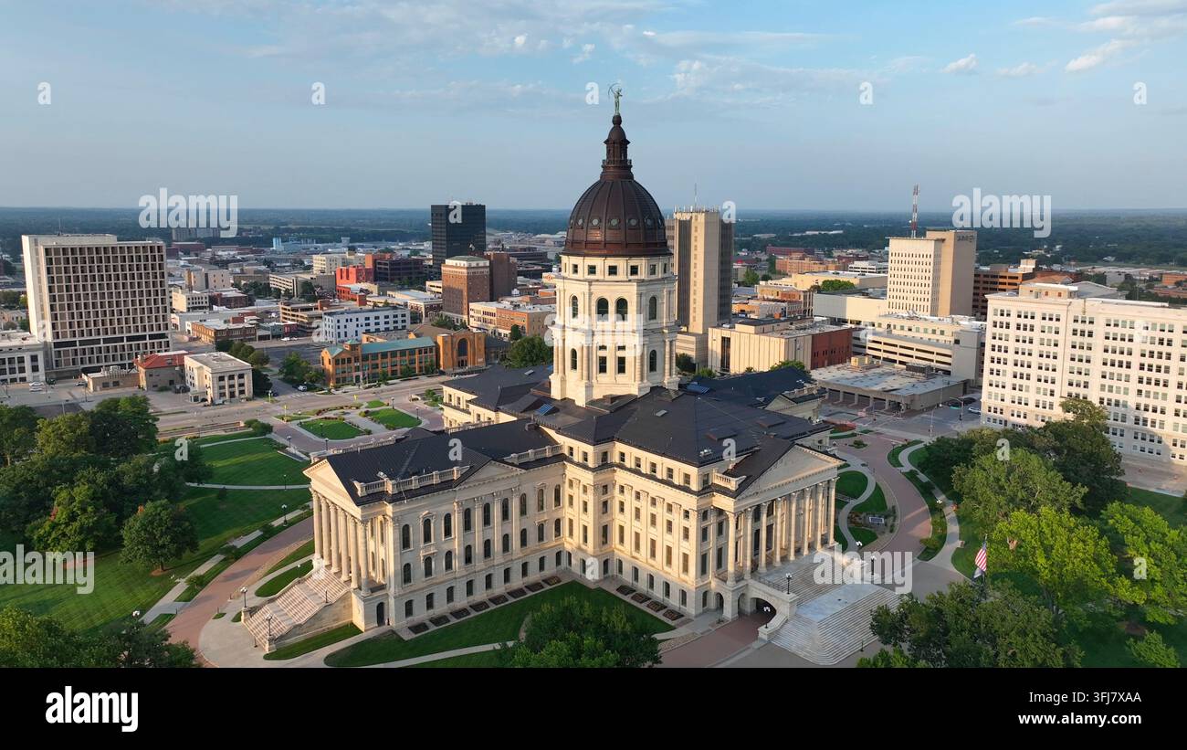 Edificio del Campidoglio dello Stato del Kansas nella maestosa luce dell'ora dorata al tramonto estivo. Ripresa aerea ascendente che rivela lo skyline del centro di Topeka, KS. Foto Stock