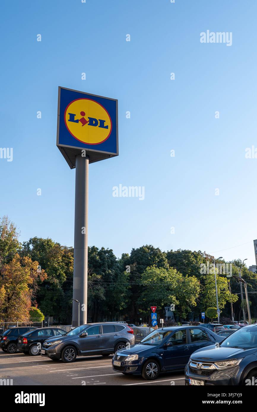 Un grande cartello del supermercato Lidl che si erge sopra un parcheggio con auto parcheggiate sotto un cielo sereno a Drumul Taberei, Bucarest, Romania Foto Stock