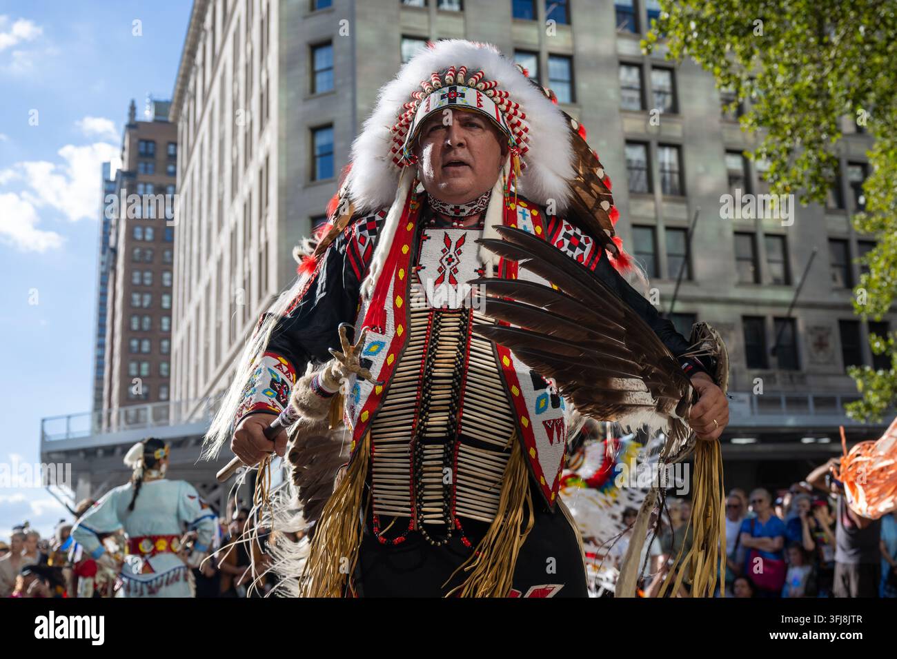 Gli anziani Lenape e i ballerini tradizionali accolgono il bufalo mentre pupazzi di bufalo a grandezza naturale sfrecciano per le strade di Lower Manhattan come parte del Foto Stock