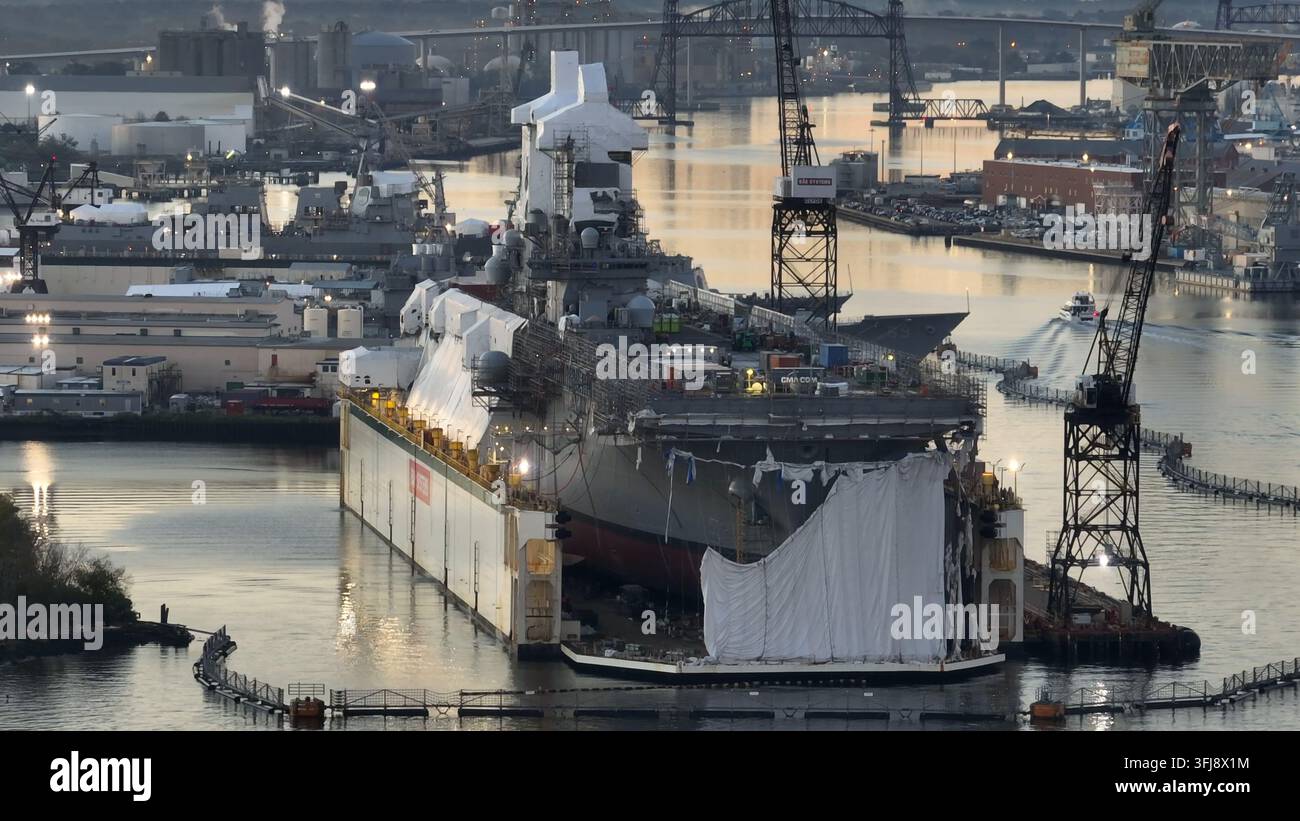 Nave da guerra in bacino di carenaggio in un cantiere navale all'alba. Ripresa aerea di riparazioni di navi della marina americana, Portsmouth, Virginia. Foto Stock
