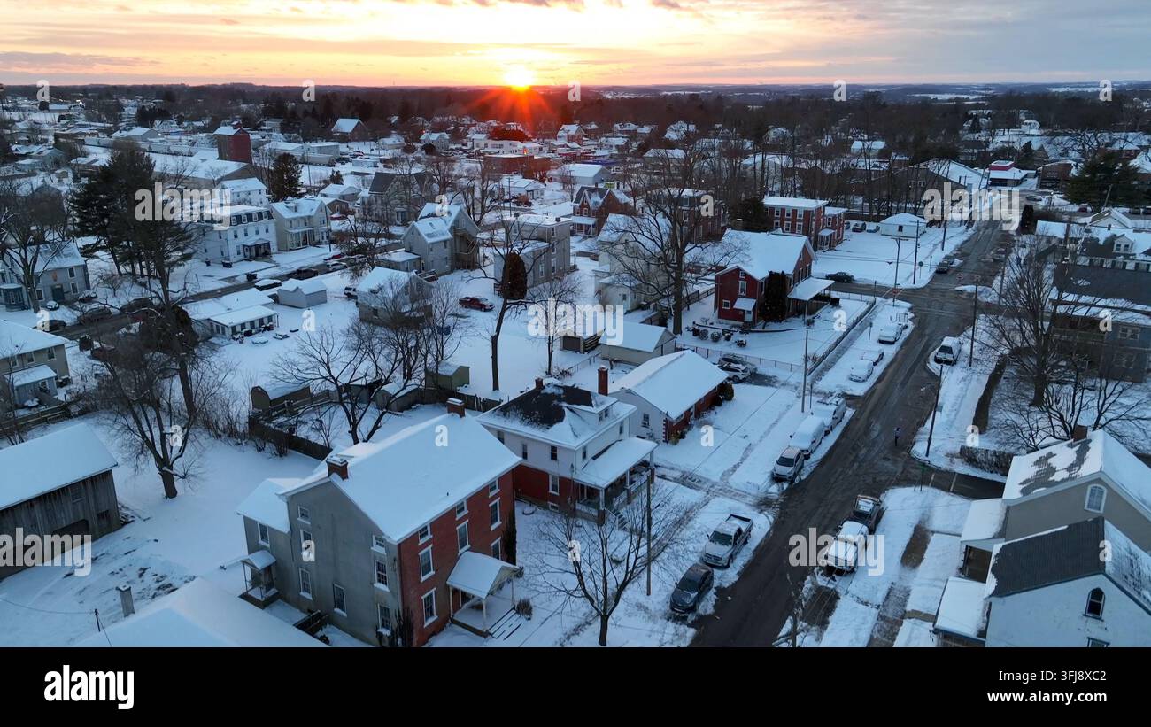 Ripresa aerea ascendente di un tramonto in inverno. Case di periferia con neve, Oxford, Pennsylvania. Foto Stock