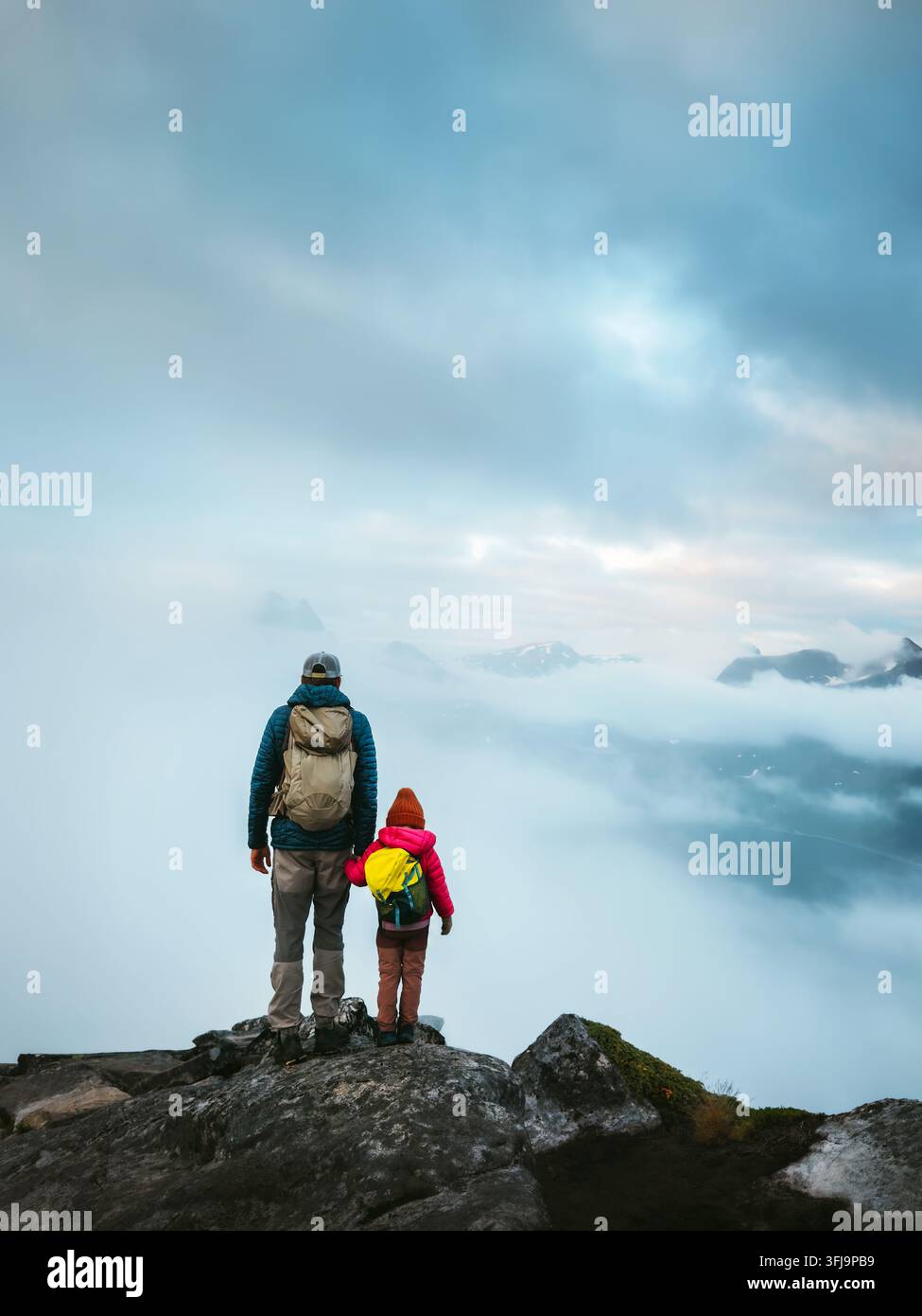 Padre e figlia in escursione nelle montagne nebbiose con zaini, vacanze attive in Norvegia, genitore e figlia esplorano Senja durante avventure all'aperto Foto Stock