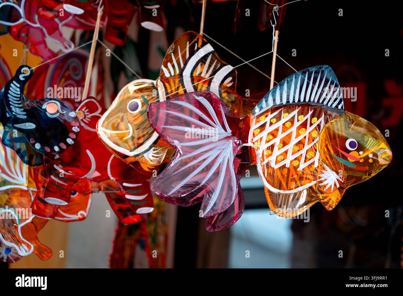Lanterne colorate in cellophane fatte a mano a forma di pesce appese a una vetrina di mercato all'aperto, che mostrano l'artigianato tradizionale asiatico per la Festa della Mezza Autunno Foto Stock