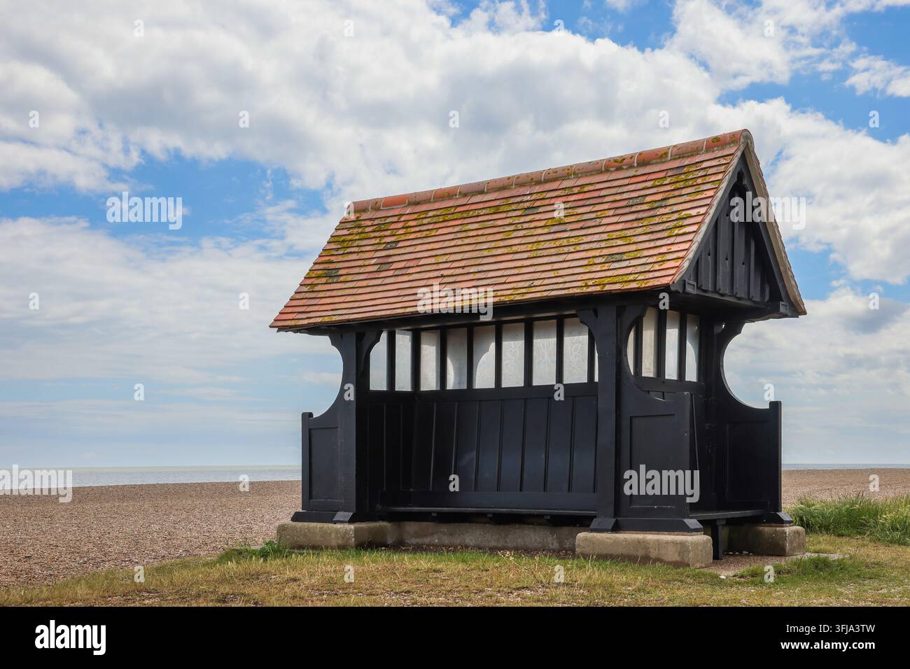 Tradizionale rifugio da spiaggia in legno verniciato di nero sulla spiaggia di ciottoli di Aldeburgh, Suffolk, Inghilterra Foto Stock