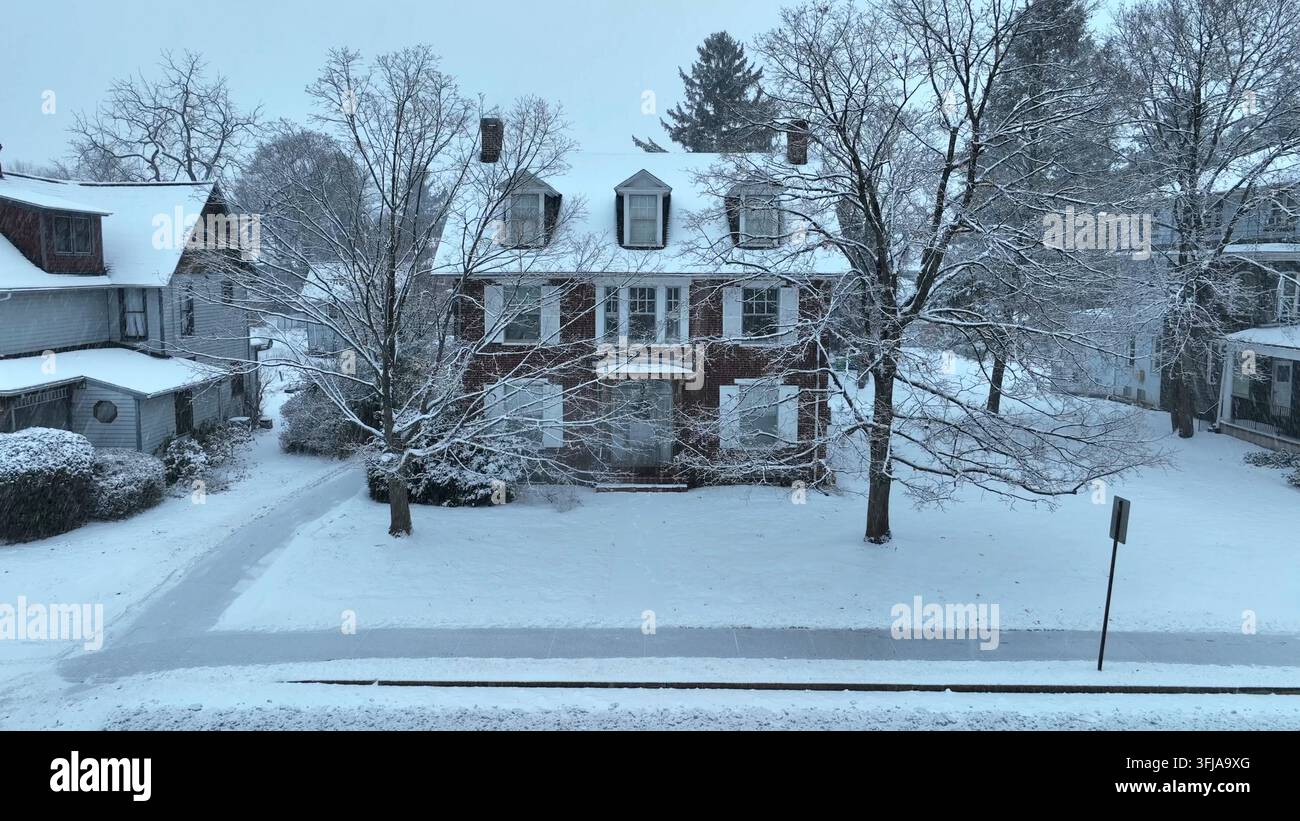 Case tradizionali ricoperte di neve e alberi costeggiano una tranquilla strada residenziale. Città storica americana durante i fiocchi di neve invernali. Veduta aerea, Gettysburg, Penns Foto Stock
