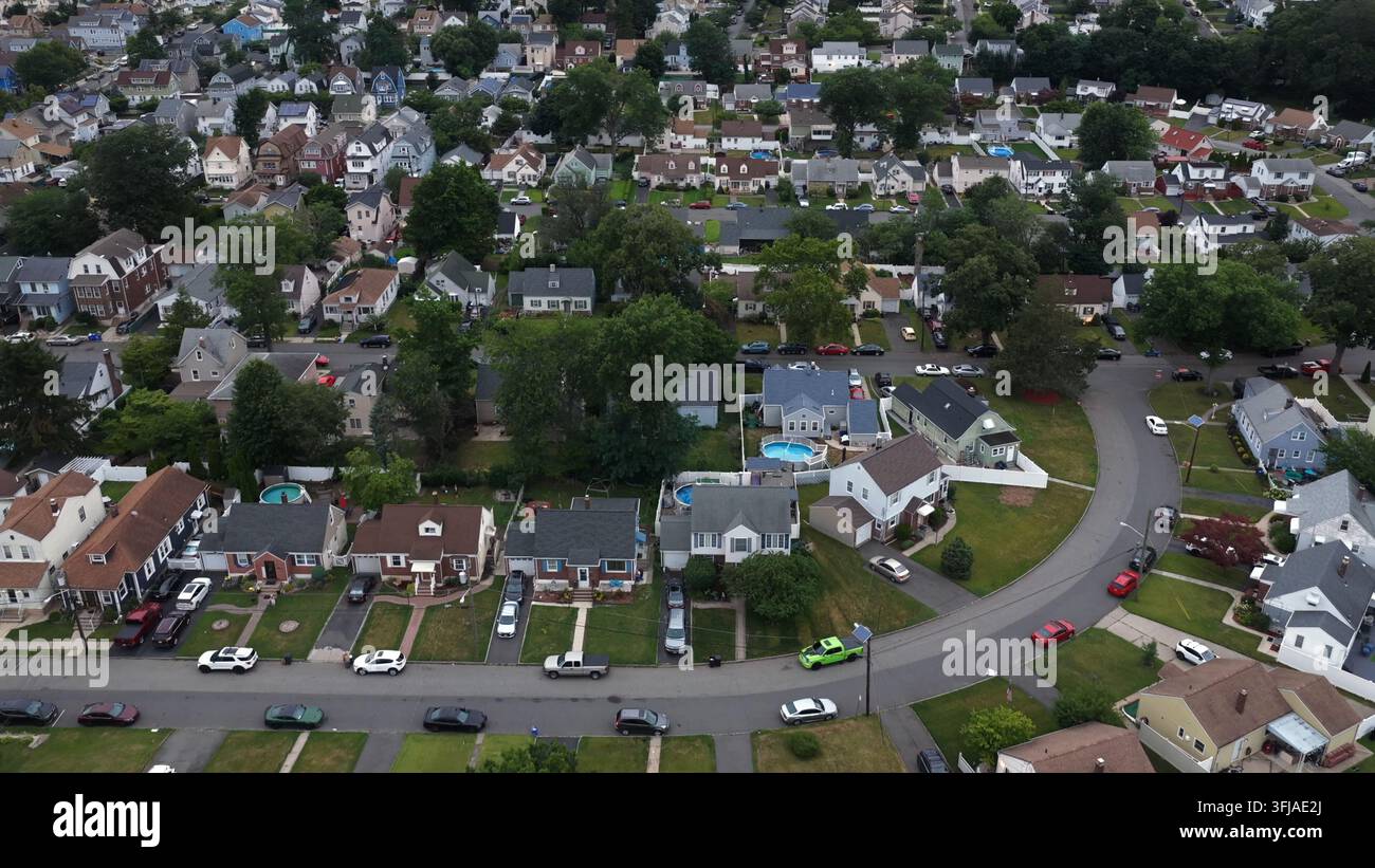 Case di un quartiere residenziale denso costeggiano una strada curva a Belleville, nel New Jersey, alberi maturi ombreggiano i vialetti e le auto parcheggiate vicino a una rotonda circolare Foto Stock