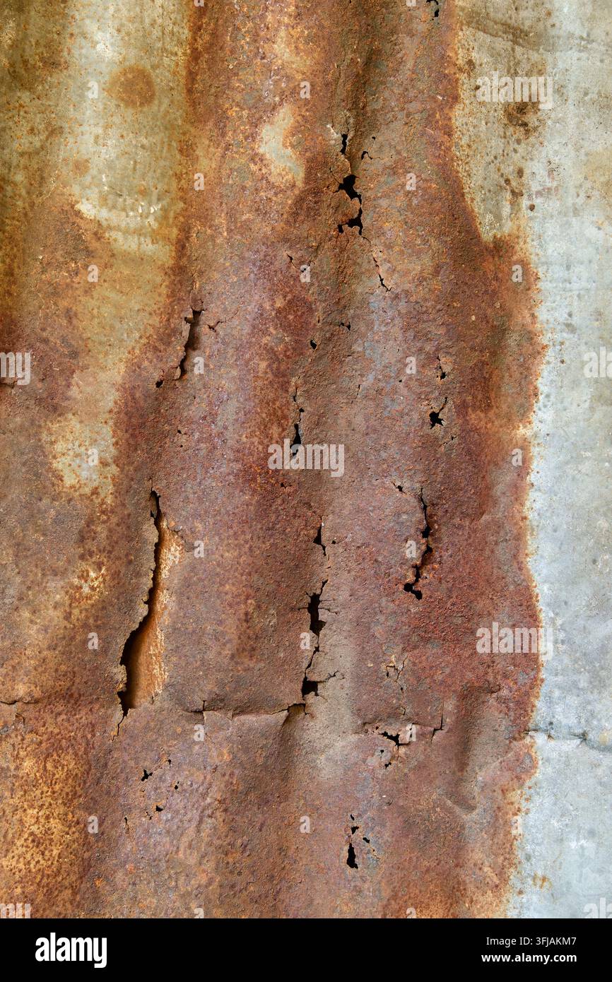 antico sfondo di lamiera metallica ondulata arrugginita, superficie in ferro consumata con ruggine marrone scuro e crepe in primo piano, decadenza industriale Foto Stock