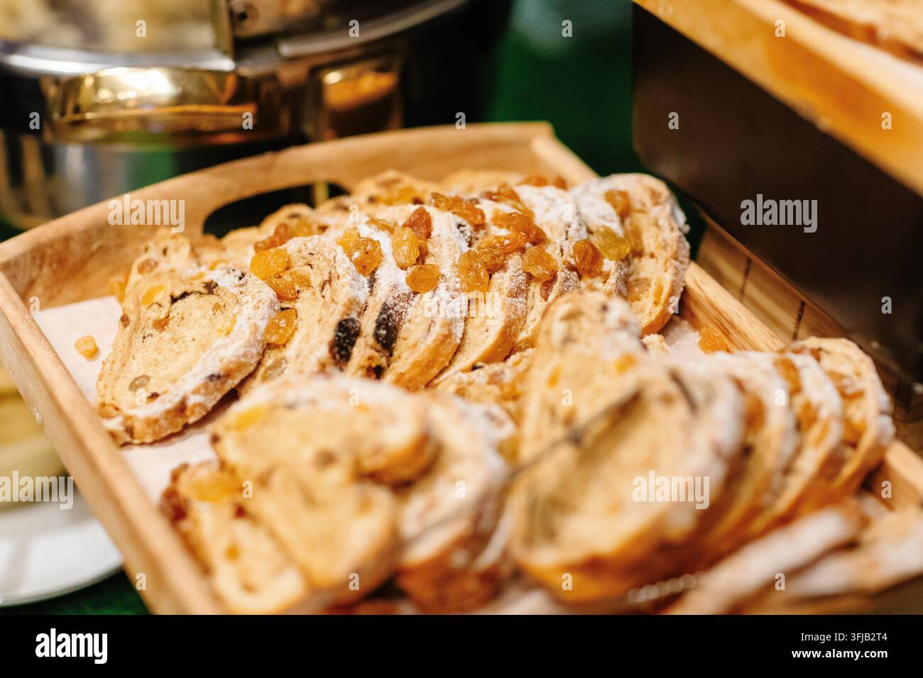 Pane ai frutti tagliato a fette con uvetta e zucchero a velo su un vassoio di legno a un buffet Foto Stock