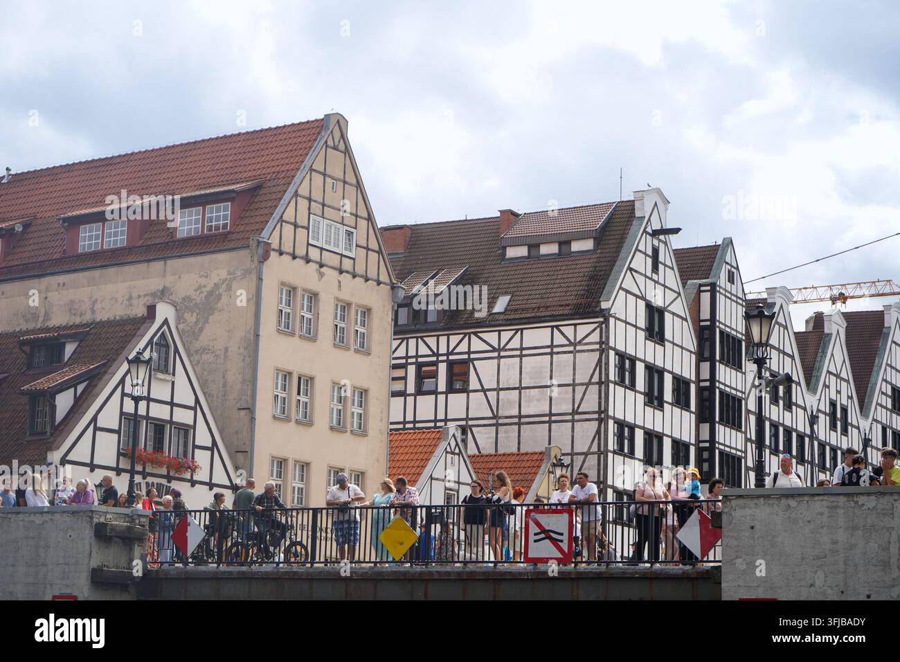 Architettura in stile mezza-timber ricostruita sull'isola del Granaio con turisti che attraversano il ponte verde nella vecchia città di Danzica, Polonia. Foto Stock
