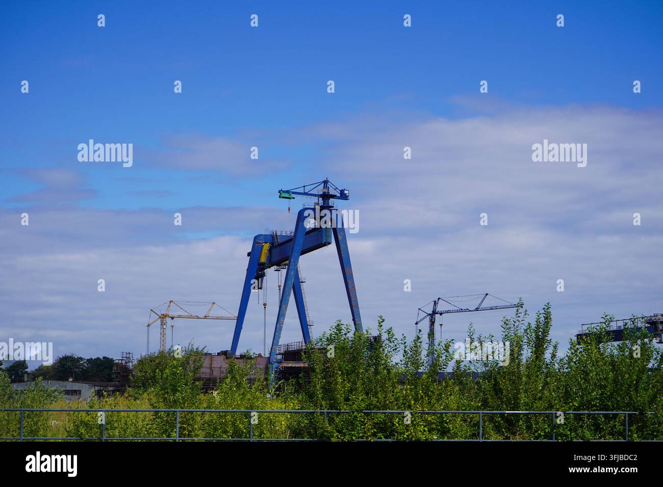 Griglia industriale pesante che si erge sulle strutture del cantiere navale vicino a Westerplatte sotto un cielo sereno. Foto Stock