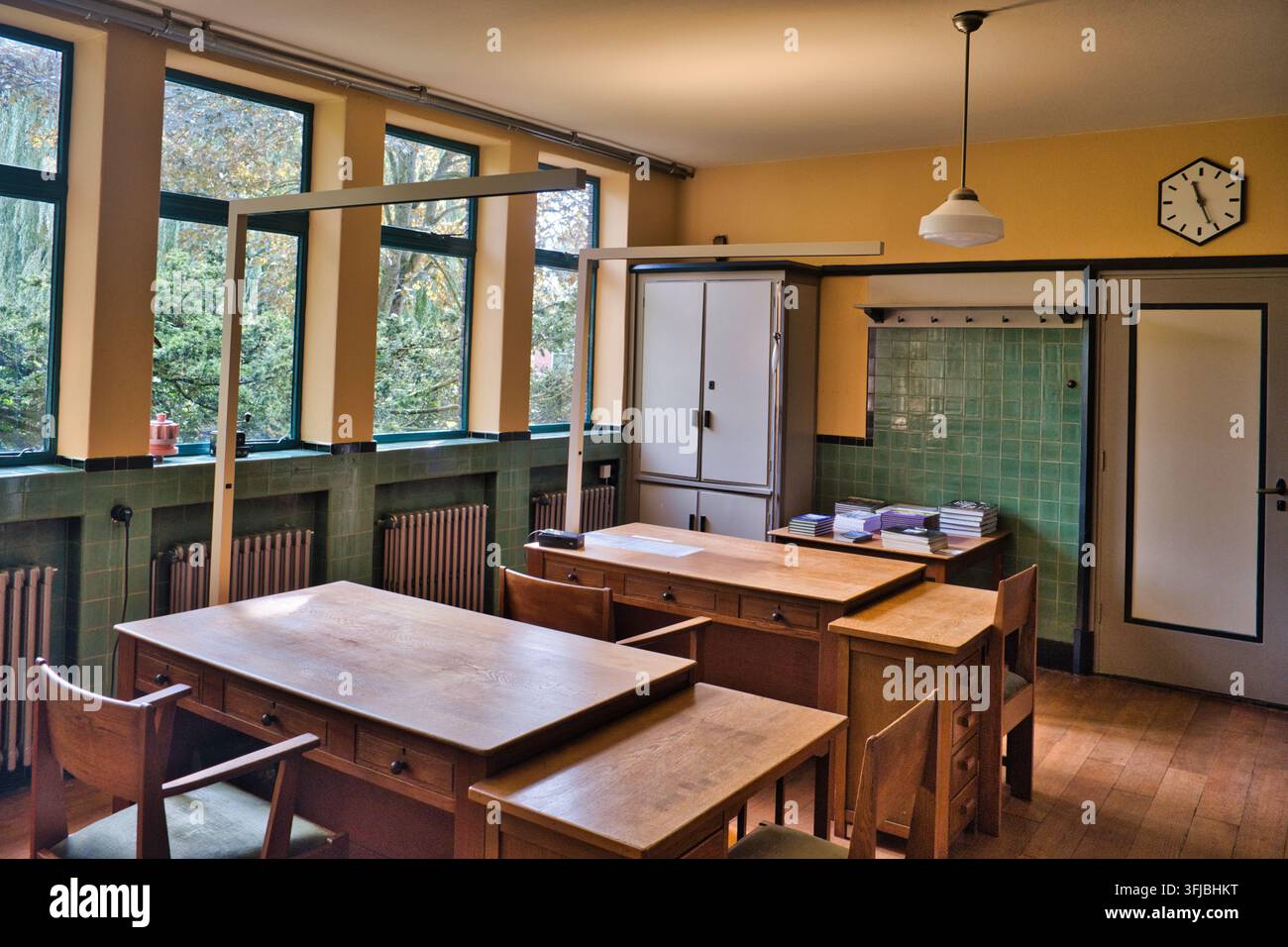 Una stanza ufficio vintage in stile anni '30 con mobili in legno, radiatori e grandi finestre. Foto Stock