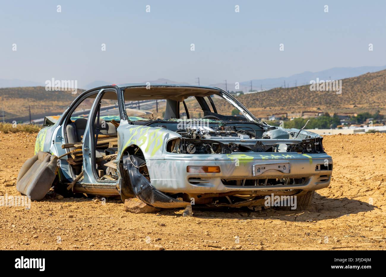 Una berlina argentata abbandonata e spogliata, posizionata su un paesaggio secco e terroso del Painter Valley Lookout a Reno, Nevada Foto Stock