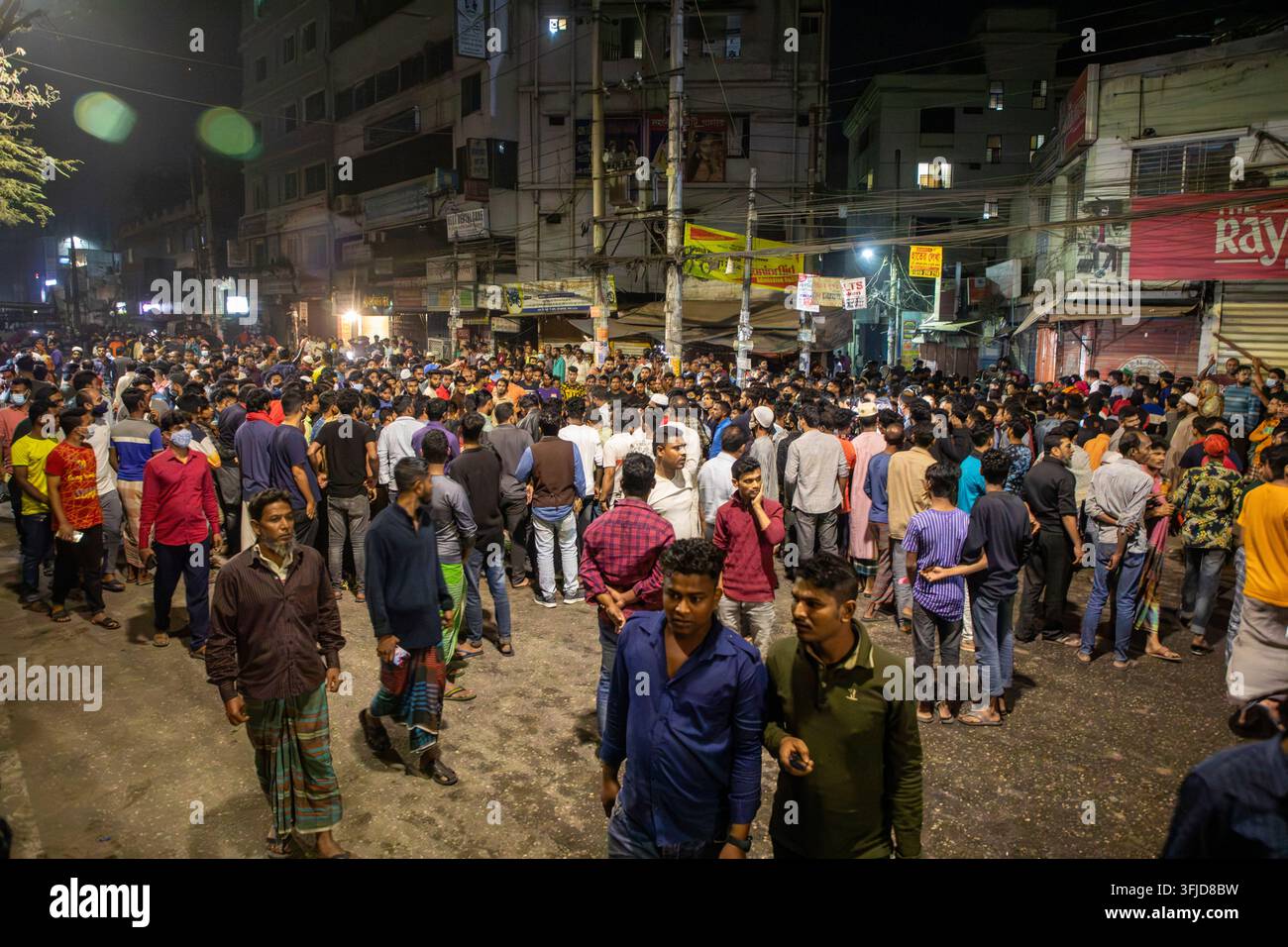 Spettatori curiosi si radunano intorno a diversi autobus dati alle fiamme nell'area di Rampura di Dhaka il 30 novembre 2021. Gli autobus sarebbero stati appiccati al fuoco da persone arrabbiate Foto Stock