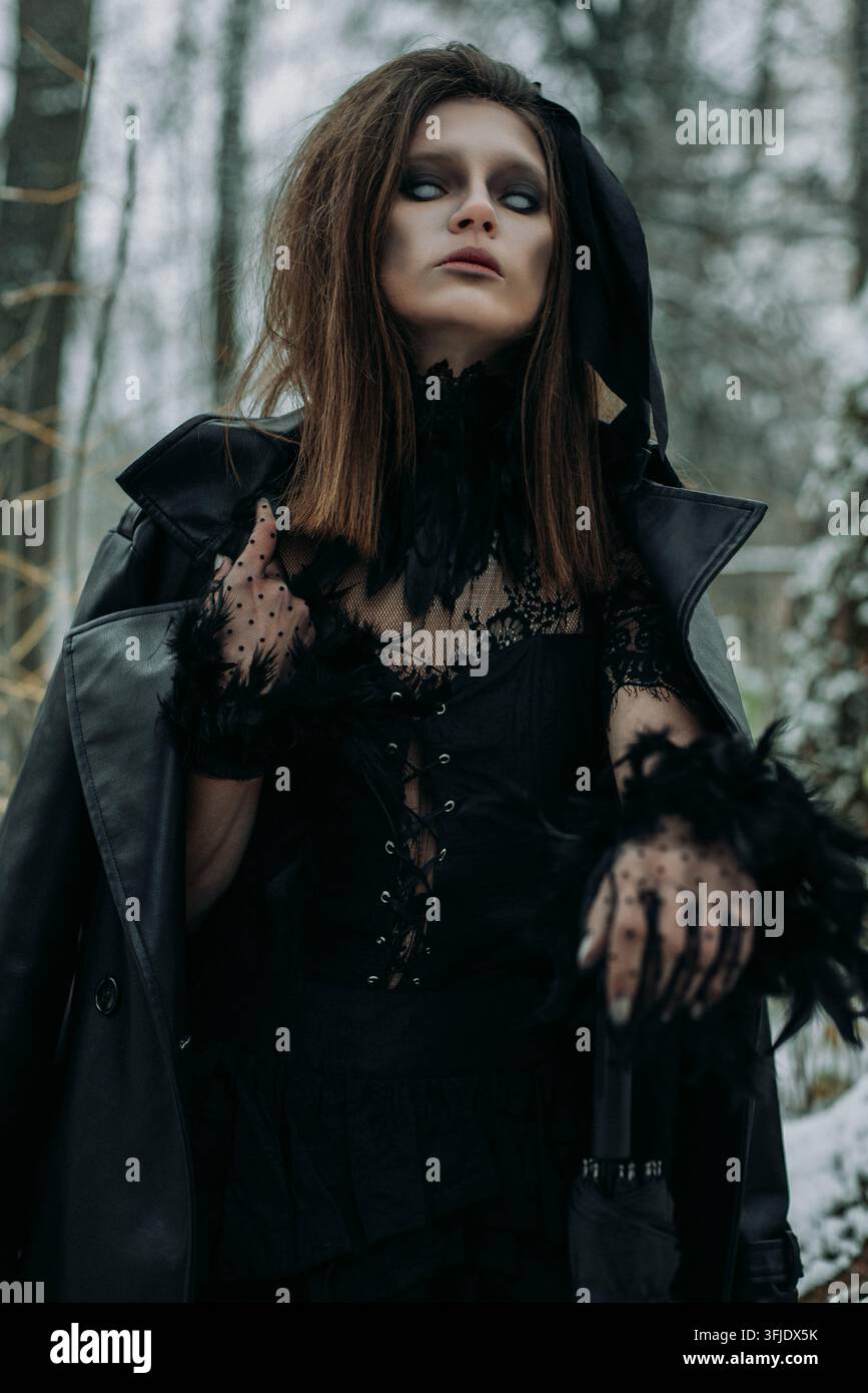 Strega misteriosa cammina nella foresta notturna. Fumo di nebbia, foschia. Regina gotica spaventosa Foto Stock