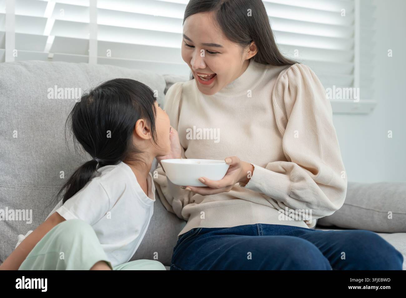 attività insieme durante le vacanze. Mamma e figlia stanno mangiando insieme, mamma prepara la colazione per la figlia la mattina, buon divertimento, settimana Foto Stock