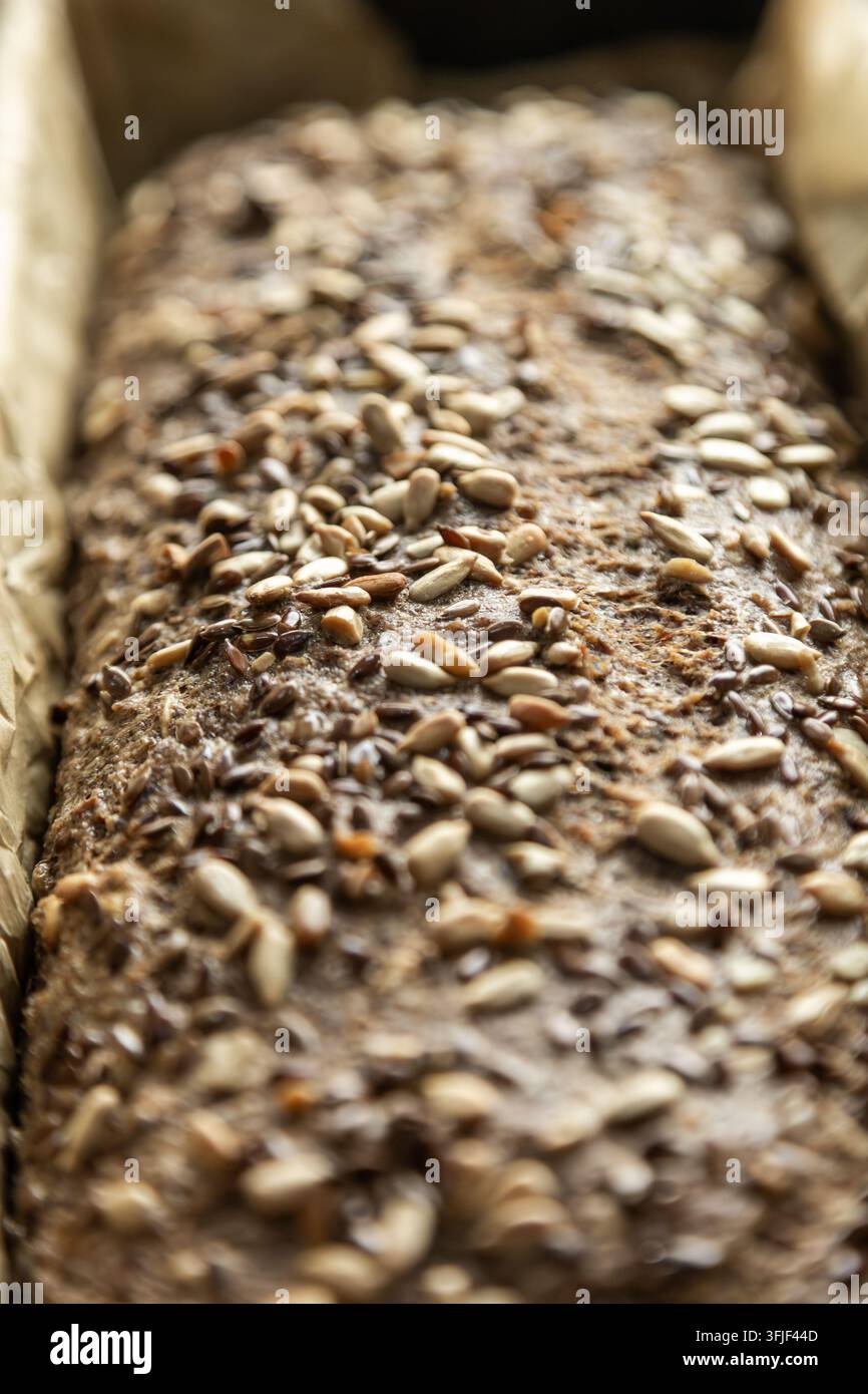 Pane artigianale integrale ricoperto di semi misti in una teglia da forno Foto Stock
