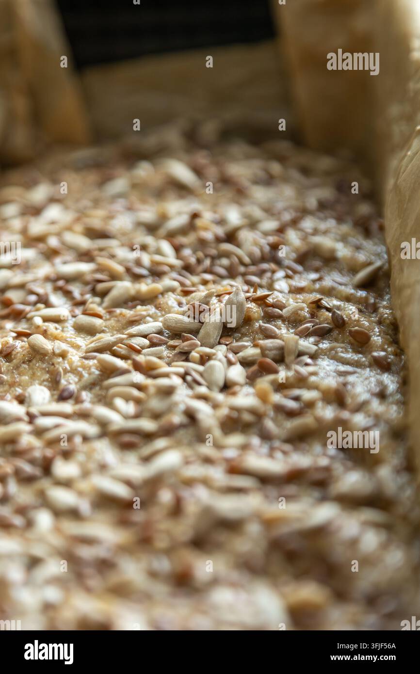 Pane non cotto preparato per la cottura e guarnito con semi misti Foto Stock
