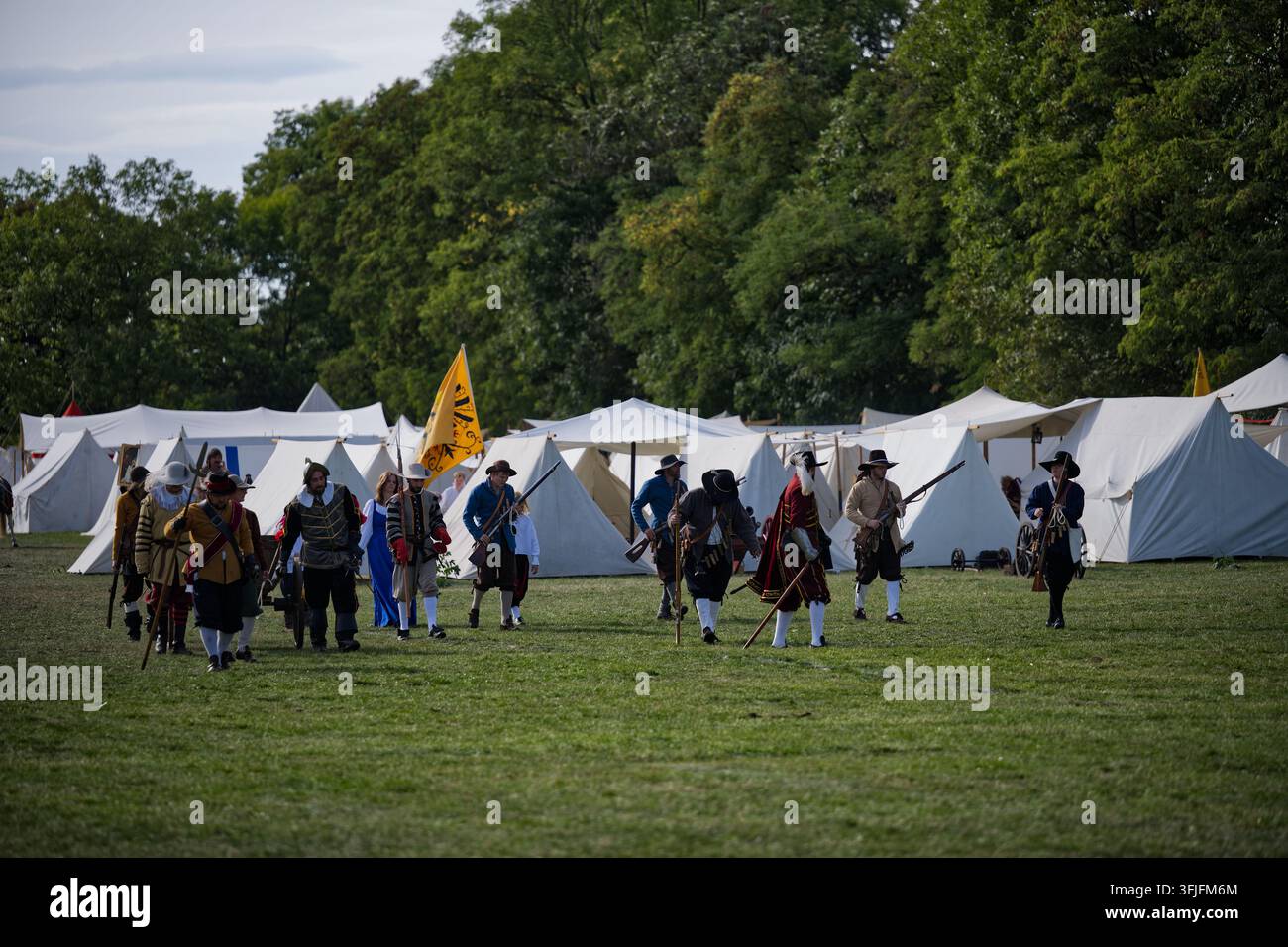 Ricostruttori in abiti militari del XVII secolo camminano attraverso un accampamento d'epoca durante la rievocazione della battaglia di Bianca Montagna. Foto Stock