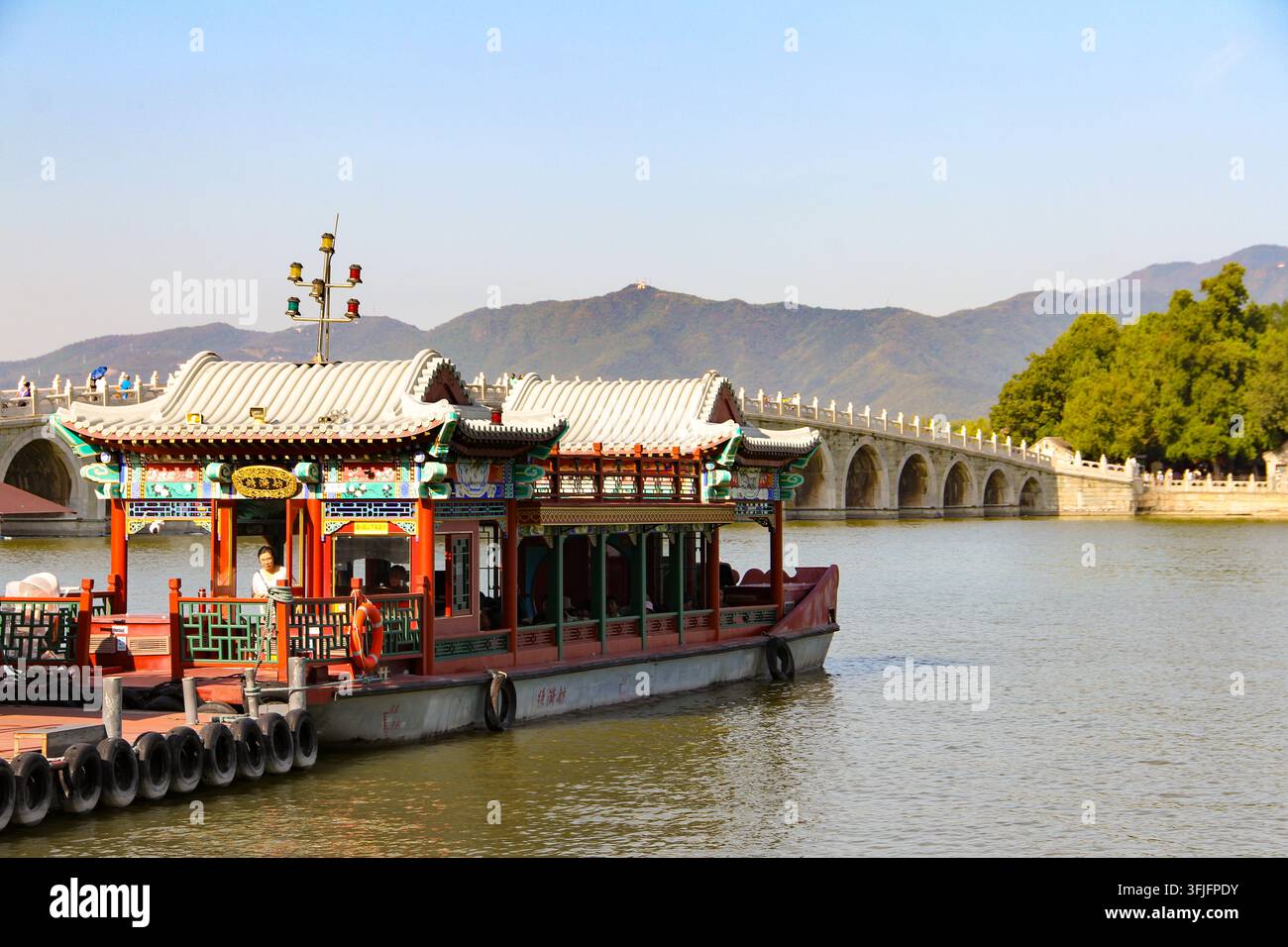 Barca da piacere tradizionale cinese ornata ormeggiata davanti al Ponte dei Diciassette Archi e alle montagne del Palazzo d'Estate a Pechino, Cina. Foto Stock