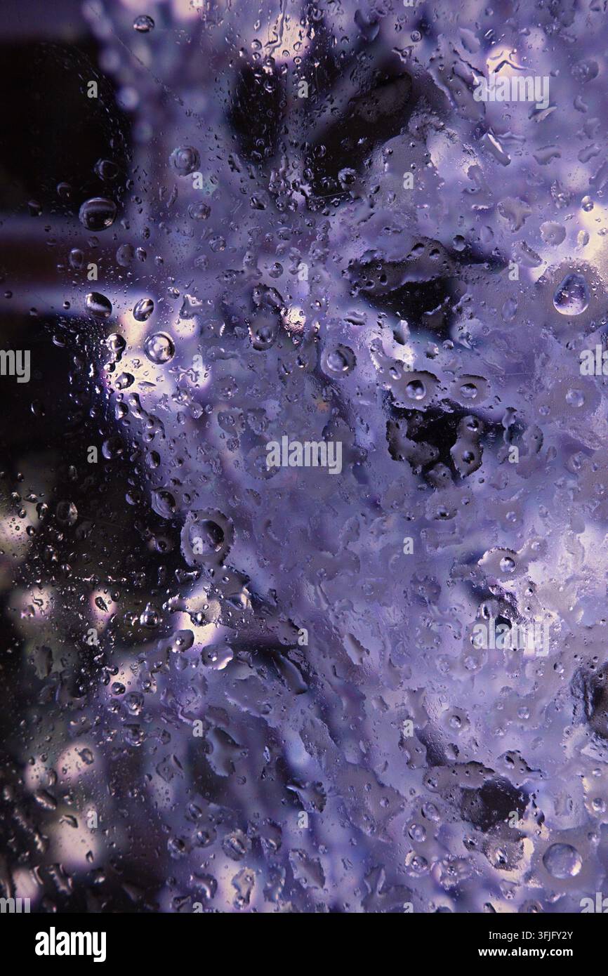 Una texture astratta con gocce d'acqua o un motivo di ghiaccio sul vetro nelle tonalità del viola. Foto di alta qualità Foto Stock