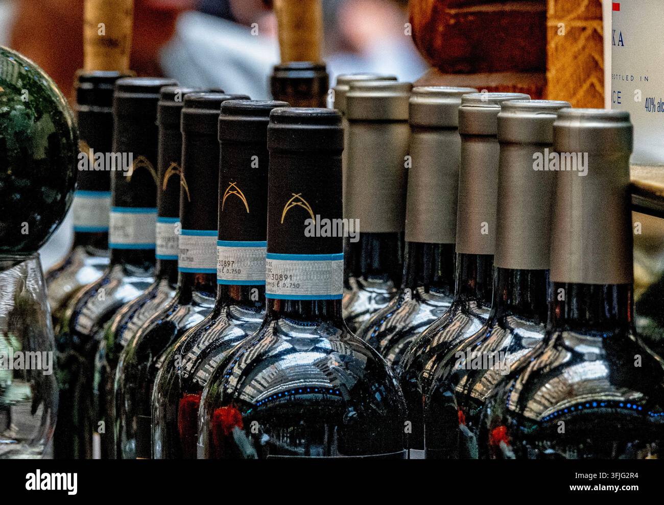 Una fila di bottiglie di vino Produttori di Manduria Lirica Primitivo di Manduria con colli di foglio scuro distintivi e bande di collo DOC italiane. Foto Stock