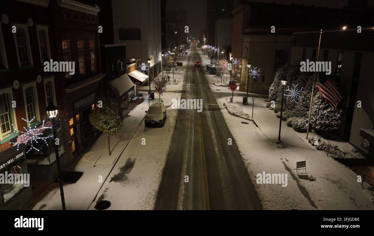 Scena notturna della strada principale innevata del centro città in America. Ripresa aerea. Strada decorata con fiocchi di neve e nevicata notturna. Bandiera americana di Foto Stock
