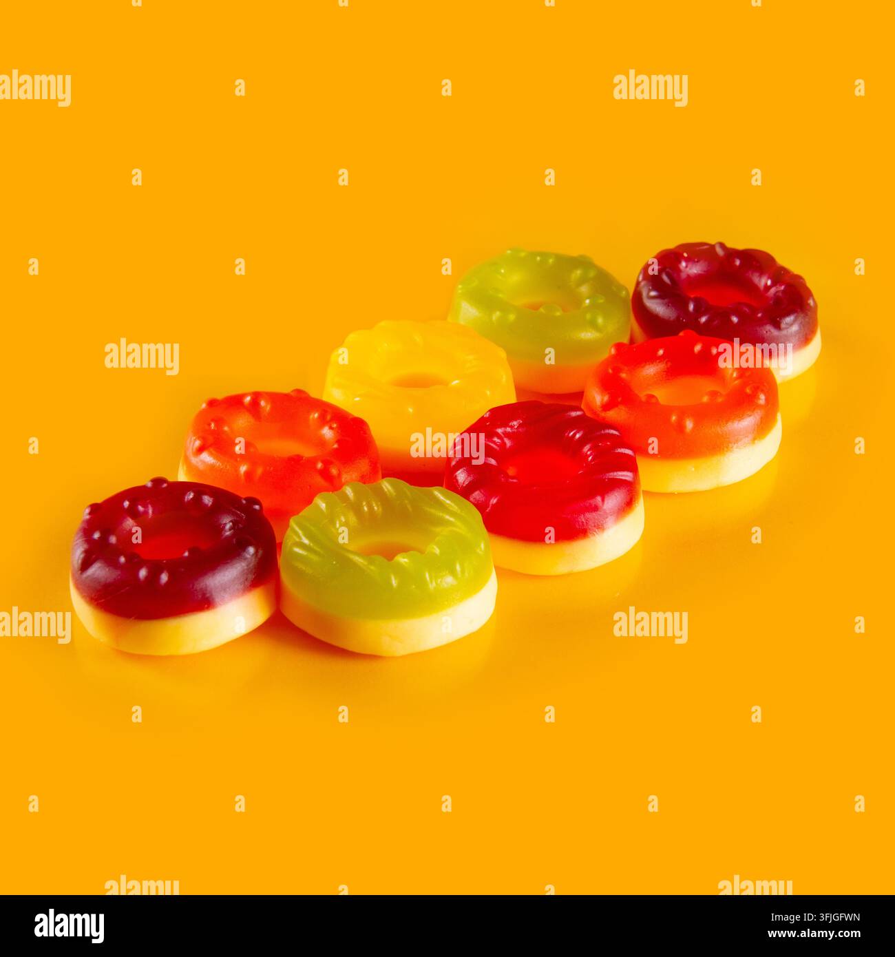 Alcuni dolci in gelatina giacciono su uno sfondo arancione chiaro. Un arcobaleno di deliziose caramelle rotonde Foto Stock