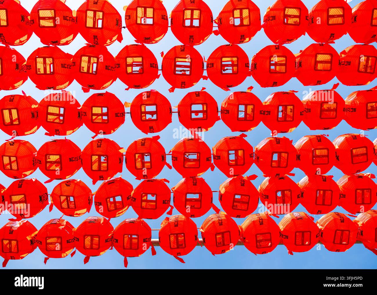 Vista di file di lanterne rosse vivaci appese contro un cielo blu chiaro a Seoul, Seoul, Corea del Sud. Foto Stock