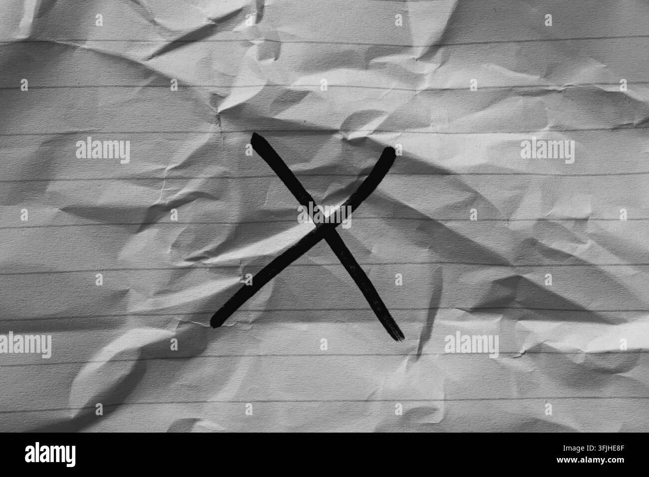 Segno X nero dipinto su carta rigata bianca accartocciata Foto Stock