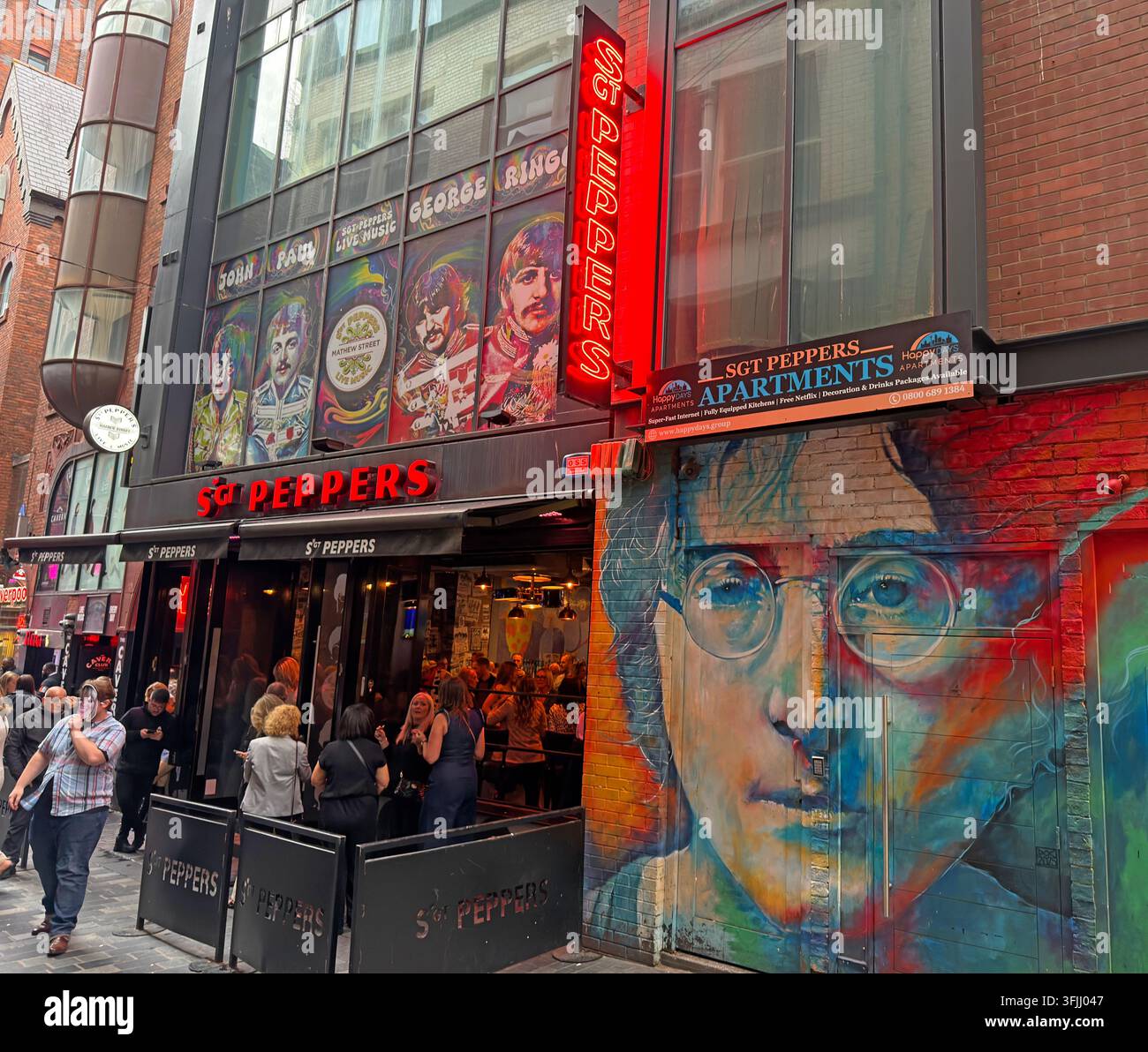 Bar e camere Sgt Peppers, locale di musica live in Mathew Street, Liverpool, con un grande murale di John Lennon nel Cavern Quarter, turisti degli anni '60 Foto Stock